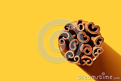Cinnamon sticks in round glass on deep yellow background. Poster, banner with copy space. Cross section of cassia tree bark. Stock Photo