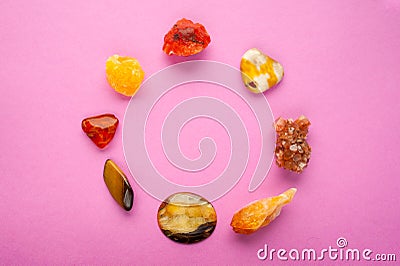 A circle of different minerals on pink background. Spiritual amber, calcite, Aragonite, Simbercite, Jasper, Tiger`s eye Stock Photo