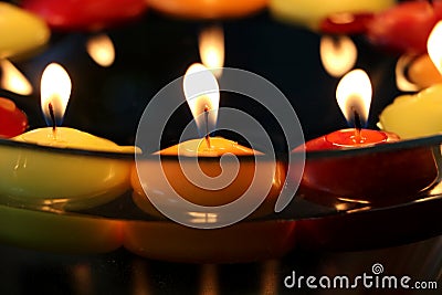 Circle of many candles in colors: yellow and orange red Close-up image. Floating above water. In a bowl. celebration. Stock Photo