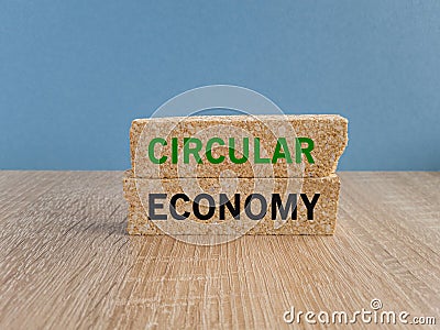 Circular economy symbol. Concept green words Circular economy on brick blocks. Beautiful wooden table blue background. Business Stock Photo
