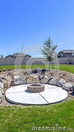 Circular fire pit surrounded by rocks in the middle of the grassy yard of a home Stock Photo