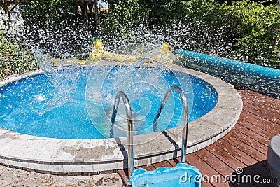 Circular outdoor pool. Water sprays from the pool. The young man jumped into the pool and the water sprang out. Stock Photo