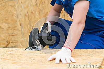 Circular saw in the hands of a man sawing a wooden plank, close-up Stock Photo