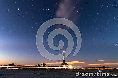 Circular star trails revolving around Polaris with a lighthouse beacon in the foreground. Fire Island lighthouse, NY Stock Photo