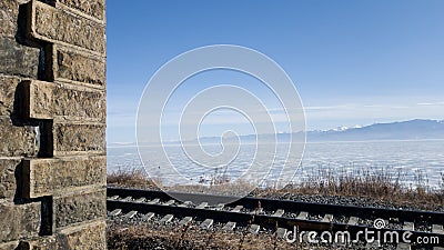 Circum-Baikal railway in winter and spring. Lake Baikal in ice, rails, part of the old tunnel wall in the frame Stock Photo