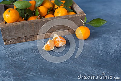 Citrus. Bright ripe tangerines with green leaves in a wooden bo Stock Photo