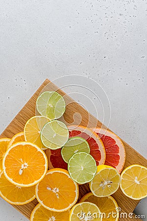 Citrus composition on chopping board. Many halved lemons, limes, grapefruits. Vertical, copy space Stock Photo