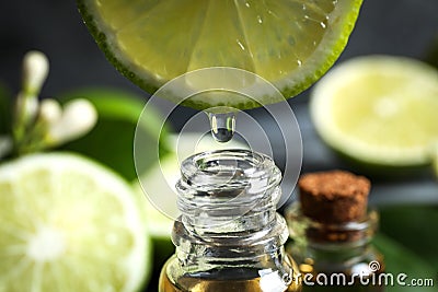 Citrus essential oil dripping from lime slice into bottle Stock Photo