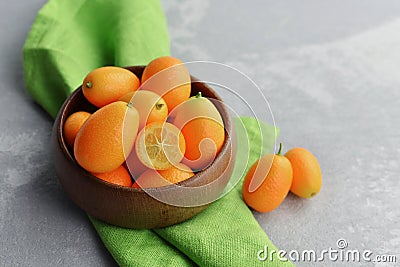 Citrus kumquat fruits in wooden bowl on linen cloth background. Healthy vegan food Stock Photo