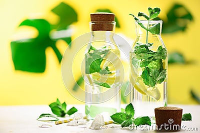 Citrus lemonade - mint, lemon and tropical monstera leaves on yellow background. Detox drink. Summer fruit infused water Stock Photo