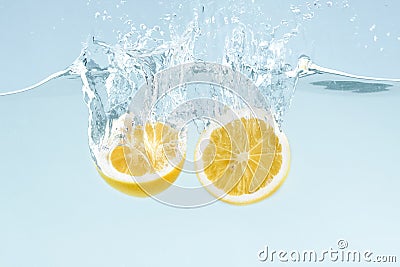 Citrus splash. Lemon halves splattering into clear water on blue background Stock Photo