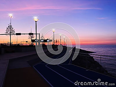 city Evening promenade at port pier city light people walking on horizon sunset pink sea and sky panorama Tallinn Estonia Stock Photo