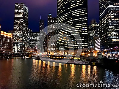 City night lights reflect onto a nearly frozen Chicago River in the loop during winter evening rush hour. Stock Photo