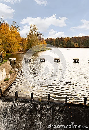 City park in autumn with a lake and a small waterfall with blue skies. Natural landscape Stock Photo
