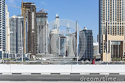 City scape with modern high-rise buildings, street and with man walking in walk way and blue sky in background at Dubai Editorial Stock Photo