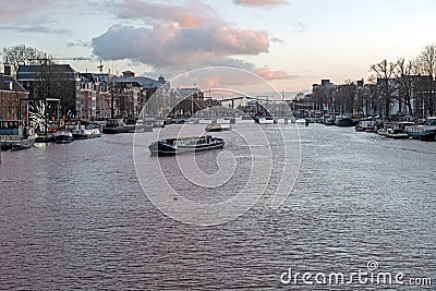 City scenic from Amsterdam at the Amstel in the Netherlands with the Tiny Bridge at sunset Stock Photo