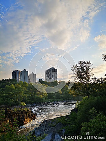 City skyline with a cascading river against a sunset Stock Photo