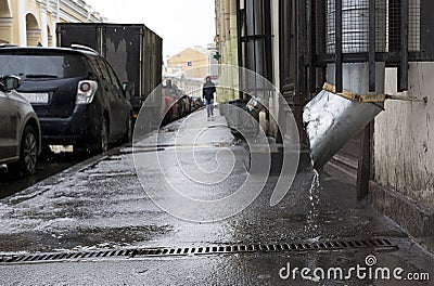 City street, man walking on the sidewalk, the rain, cars parked Stock Photo