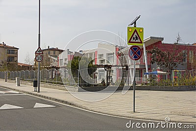 City street with a pedestrian crossing, a speed bump and a caution sign `children` near a beautiful kindergarten. Stock Photo