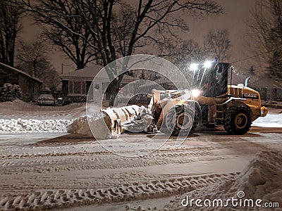 Service snow plowing truck cleaning residential street during heavy snowstorm, Toronto, Ontario, Canada. Editorial Stock Photo