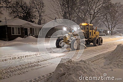 Service snow plowing truck cleaning residential street during heavy snowstorm, Toronto, Ontario, Canada. Editorial Stock Photo