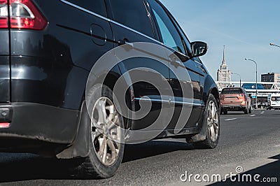 City trafic on the road. Part of black minivan car with selective focus drives on Moscow streets. Side rear low angle view on the Stock Photo