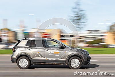 The CityBee car sharing vehicle drives quickly down the street, side view. Motion blur. Riga, Latvia - 09 Sep 2021 Editorial Stock Photo