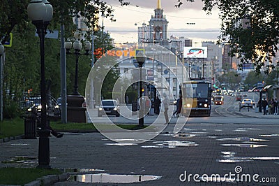 Cityscape. Alley, puddles, clouds, tram, cars, headlights. Editorial Stock Photo