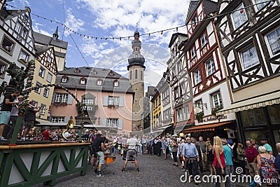 Cityscape of Cochem with its typical half-timbered houses and restaurants. Market square with town hall in background, people cele Editorial Stock Photo