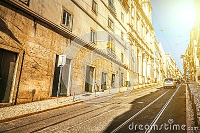 Cityscape of the old city in Lisbon with a steeply rising street with tram tracks and facades of old houses. Perspective view of Stock Photo