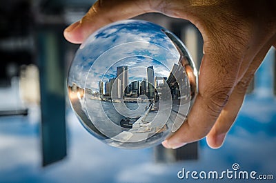 Cityscape photography in a clear glass crystal ball with dramatic clouds sky. Stock Photo