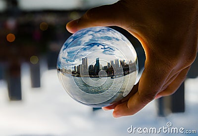 Cityscape photography in a clear glass crystal ball with dramatic clouds sky. Stock Photo