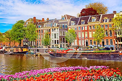 Cityscape view of the canal of Amsterdam in summer with a blue sky and traditional old houses. Colorful spring tulips flowerbed on Stock Photo