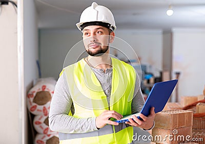 Civil engineer working on a construction site indoors monitors the process of capital repairs of a brick house on laptop Stock Photo