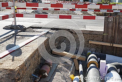 Civil engineering building site with thick pipes covered by layer of insulation foam, secured by red and white barrier planks Stock Photo