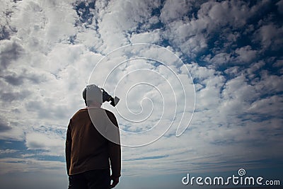 Civilian man wearing military gas mask. Human silhouette in a gas mask against moody sky. Atmospheric pollution, environmental Stock Photo