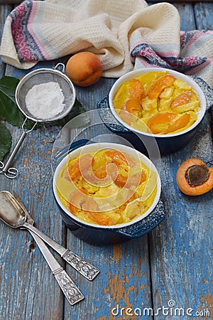 Clafouti with apricots in rameken on blue wooden background. Fruits clafoutis. Sweet casserole. Traditional French cake. Copy Stock Photo