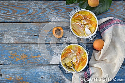 Clafouti with apricots in rameken on blue wooden background. Fruits clafoutis. Sweet casserole. Traditional French cake. Copy Stock Photo