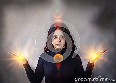 A clairvoyant girl in a trance state, a glow emanates from the palms of her hands. Stock Photo