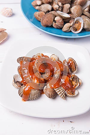 with shell on a blue plate on a white wood background with chilli and tomato sauce Stock Photo