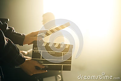 Clapperboard or clipboard in hands. Guy is directing and filming retro cinema or vintage movie. Composer man play on the old piano Stock Photo
