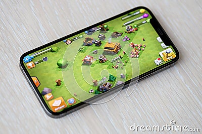 Clash of Clans mobile iOS game on iPhone 15 smartphone screen on wooden table during mobile gameplay Editorial Stock Photo