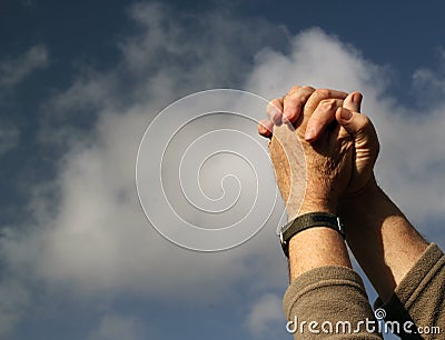 Clasped hands praying. Clouds and sky background. Stock Photo