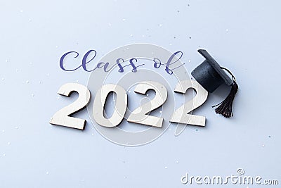 Class of 2022 wearing graduate cap on wooden number 2022 on grey background with glitter Stock Photo