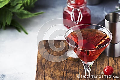 Classic alcoholic cocktail Manhattan with american bourbon, red vermouth, bitter, ice and cocktail cherry in glass, tools, gray Stock Photo