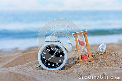 Classic analog clocks and Message or letter in bottle with hourglass in sand on the tropical beach, Time concept Stock Photo