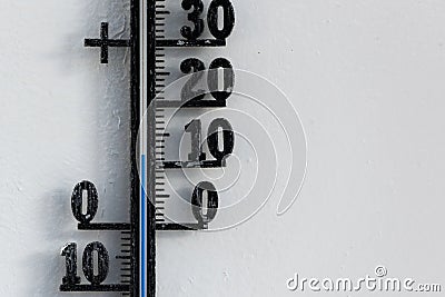 Classic analog thermometer hanging on white wall displaying warmth of twelve degrees celsius Stock Photo