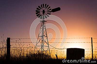 Classic Australian windmill on farmland silhouetted at sunset Stock Photo