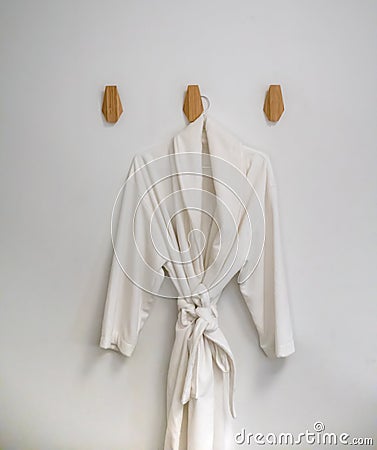 Classic bathrobe hanging on wooden abstract wall hook mounted ag Stock Photo