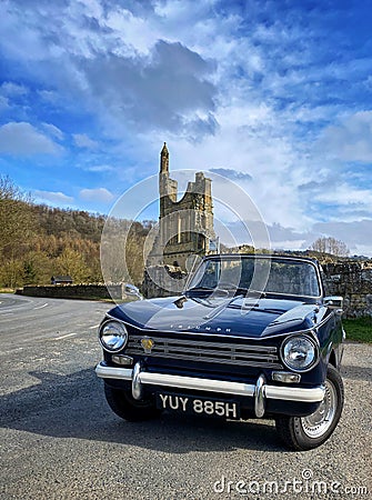 Triumph Herald 13/60 convertible parked by a ruined abbey Editorial Stock Photo